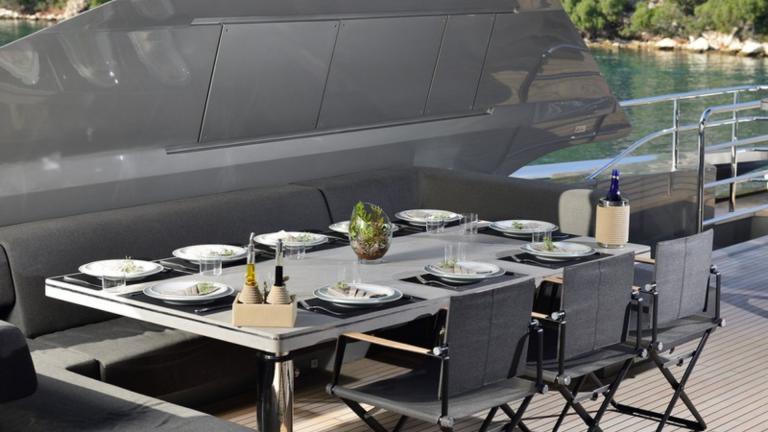 Kiralık bir yatın açık havada deniz manzarasıyla yemek yiyip zaman geçirmek isteyeceğiniz bir yemek masası.